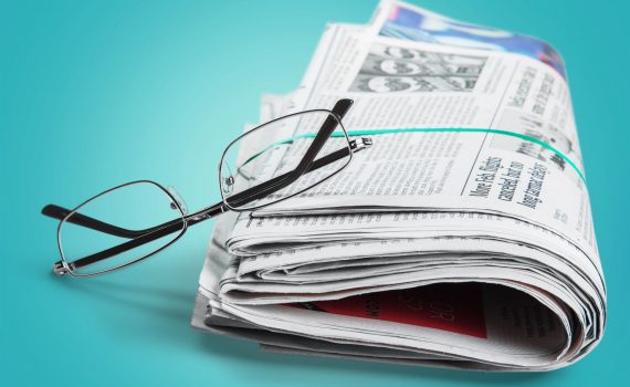תמונה של משקפיים על עיתון מגולגל - להמחשת לחצן מאמרים